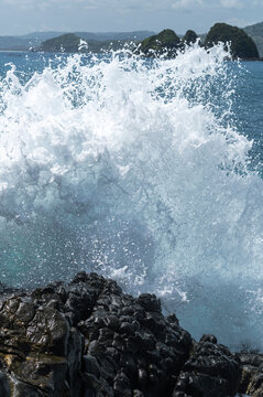  Waves crash against the rugged volcanic rocks, the power of nature. Indonesia, Asia.