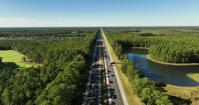 Aerial above I-95 Highway in north east part of Florida near Jacksonville. Highway among green forest, blue sky above horizon