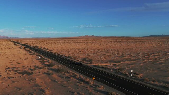 Modern car driving on a street in the desert from California to Arizona. Cinematic sunset landscape.