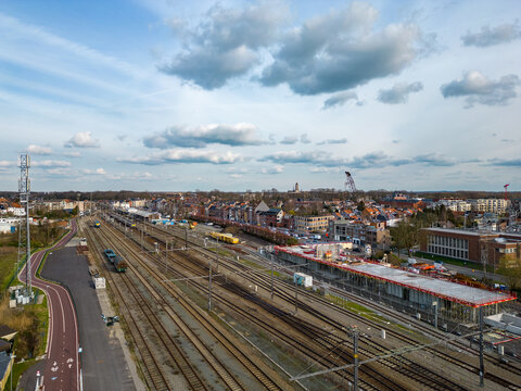 The image provides a comprehensive daytime aerial view of the Lier Railway Station in Belgium, capturing the essence of daily life and transportation. Trains are seen parked and in motion, showcasing