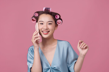 Happy lady talking on phone gossiping with friend, wearing dressing-gown and curlers