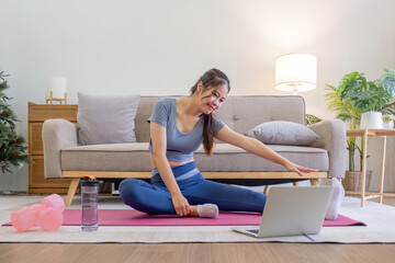 Young Asian sporty fitness woman coach do practice video online training yoga laptop in living room...