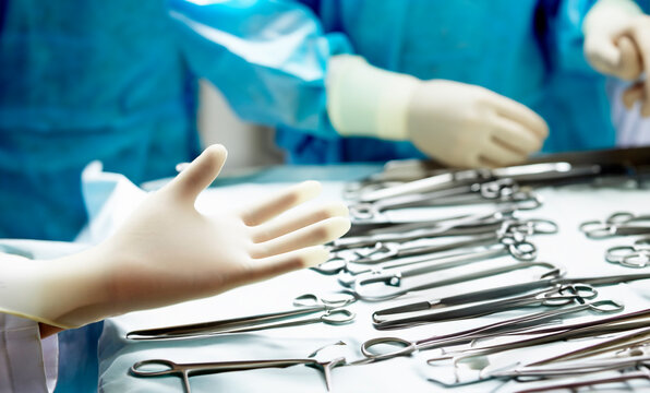 Hands wearing surgical gloves, hospital operating room background