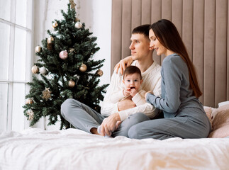 - mom and dad together with little daughter next to christmas tree, have fun, enjoy happy family life