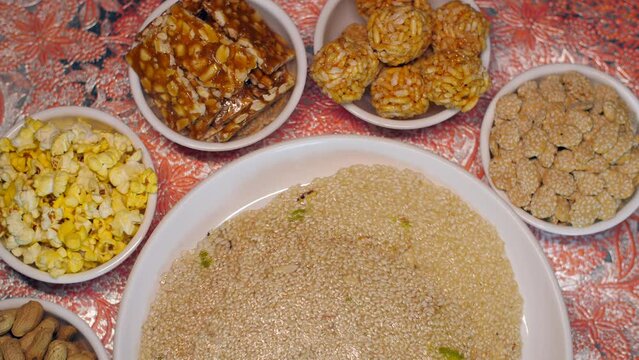 Pan shot of homemade Indian sweets decorated on the table to celebrate Lohri Festival. Til chikki  peanut chikki  murmura ladoo  revdi  popcorn  Indian festival food snack sweet for Lohri and Makar...