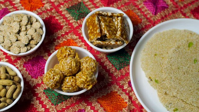 Pan shot of various sweets consumed during Indian Festival Lohri Makar Sankranti. Winter delicacy Makar Sankranti or Lohri mithai gajak  til patti or papdi  til laddu or ladoo  revdi and rewri  mun...