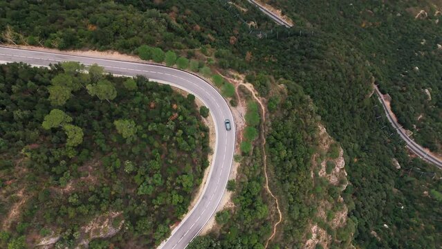 Drone top-down shot expertly following a car along a winding mountain road