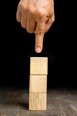 A human hand shows a stack of wooden cubes