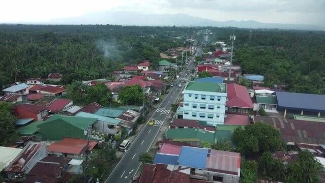 Drone shot of Philippine Province small highway road, surrounded by houses and trees