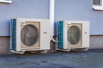 Two air source heat pumps installed outside of new and modern city house, green renewable energy...