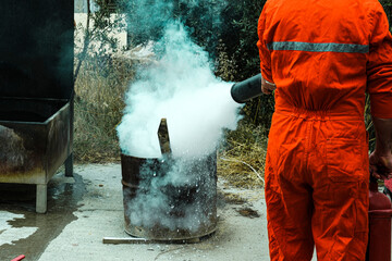 stcw firefighting prevention training, man using fire extinguisher against open fire in a barrel,...