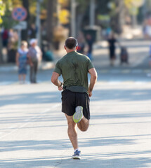 Fototapeta premium A man in shorts runs along the road in the city. Sport