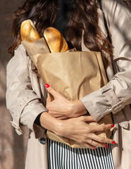 Obraz premium The girl holds a bag of bread baguettes in her hands