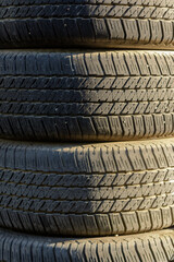 Stacked used car tires in natural light.