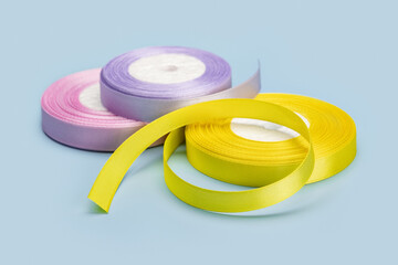 Several rolls of satin ribbon for gift wrapping. Studio shot, blue background.