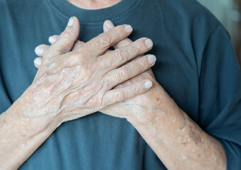 Crop close up of old man hold hands in prayer at heart chest feel religious superstitious.