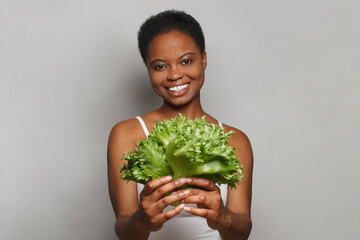 Attractive woman holding vegetable green lettuce on white background. Healthy lifestyle, Vegan,...