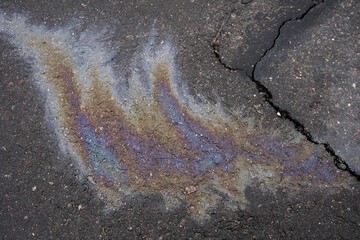 Leakage of oil or gasoline from the car on the asphalt in the parking lot.