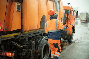 Car for cleaning road. Orange transport. Worker in special uniform.