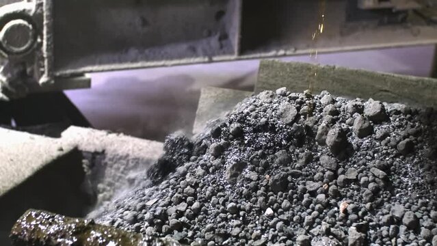 Cement factory. A conveyor with stones and gravel undergoes the crushing process. Modern technologies at a cement plant. Technological work for cement production. Close-up of raw material grinding.