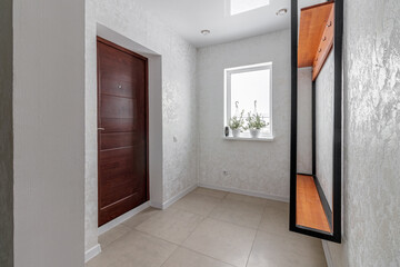 Hallway in a small country house with brown front door and clothes rack