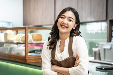 Smiling portrait of a young female asian barista working in a cafe bar, cafe staff standing near...