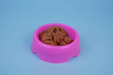 Bowl with pate cat food on blue background.	