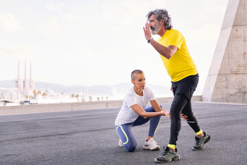 female personal trainer correcting the leg position of a senior sports man during his squat workout, concept of active and healthy lifestyle in middle age, copy space for text