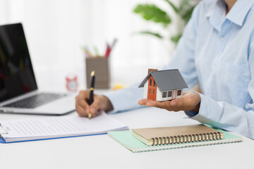 Professional real estate agent signs contract While holding a house. The concept of a home loan contract for housing.