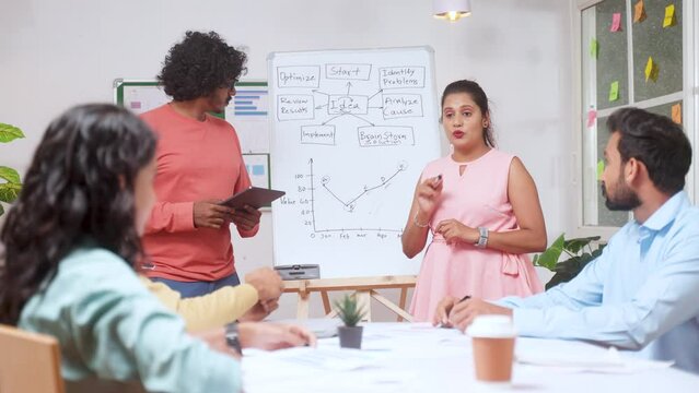 businesswoman or employee explaining during team meeting or discussion at office from white board - concept of collaboration, interactive workplace and leadership conference