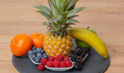 Ananas Frucht mit Himbeeren, Brombeeren, Heidelbeeren, Mandarine, Banane, Apfel, auf einer...