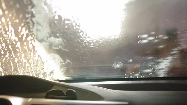 Auto detailer expertly cleanses a car with foamy cleanser and brush, restoring its brilliance. Precision and care unite in this car care masterpiece.