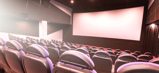 Cinema auditorium with line of red chairs, sitting visitors and silver screen. Ready for adding your own picture.