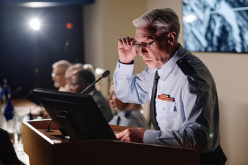Politics speaking his report in microphone at military conference with his colleagues