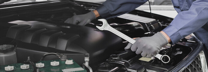 Mechanic works on the engine of the car in the garage.Concept of car inspection service and car...