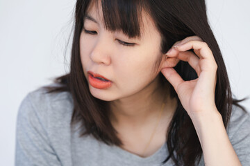 A woman has itching and irritation around her ears and inside her ears. - obrazy, fototapety, plakaty