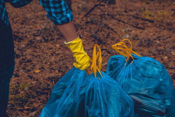 A woman volunteer puts together bags of garbage collected from the forest. A woman has collected a...