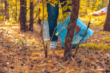 A woman volunteer collects plastic waste in the forest. A woman saves nature from being polluted by garbage. Environmental problems, plastic waste, environmental pollution.