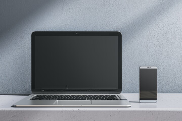 Close up of empty laptop and smartphone on gray desk. Concrete wall background. Device presentation and online education concept. Mock up, 3D Rendering. - obrazy, fototapety, plakaty