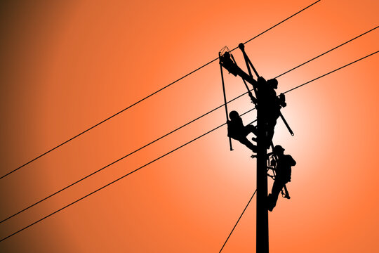 The silhouette of lineman are replacing damaged insulator insulators by using insulated wire-tong sets, tie stick and robe box sets in sliding wires going out in a safety working distance.