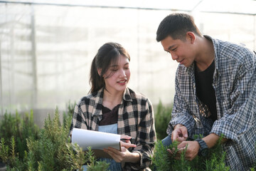 Two young asian couple farmers working in vegetables hydroponic farm with happiness