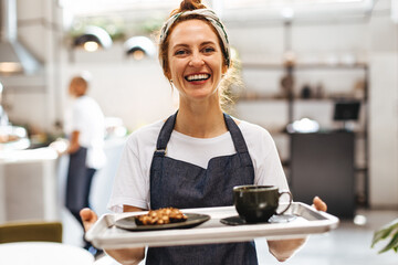 Portrait of a barista serving food and drink in a coffeehouse