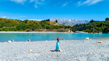 Happy holiday of young woman in blue dress in red hat as the ecosystem of the River lagoon Valley...