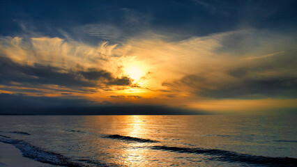Sunset on the west beach on the Baltic Sea. Waves, beach, cloudy sky. Landscape