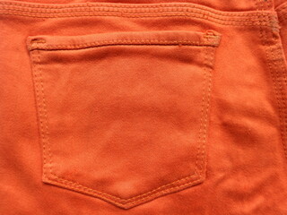 Close up of the back pocket of orange jeans