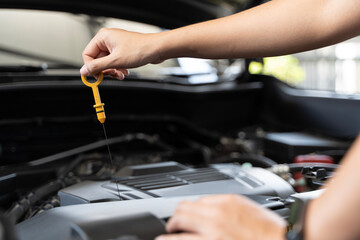 Close up of woman's hands checking oil level in car engine Woman checking oil level in car engine...
