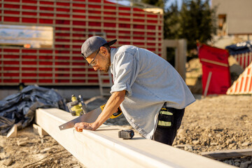 Fototapeta premium Carpenter works on a construction site, building a frame house in mountains