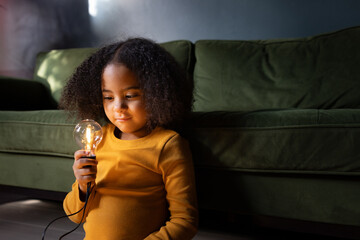 Girl looking at a lightbulb in evening light smiling