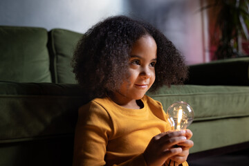 Girl holding a lightbulb in evening light smiling