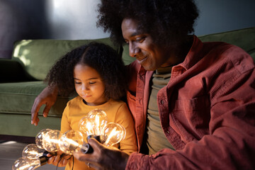 Father and daughter looking at festoon lights together in the evening light